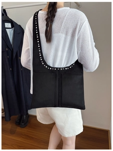 Vue arrière du sac cabas noir avec rivets et poches avant porté par un modèle