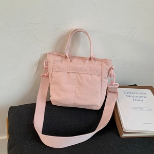 Macro shot of light pink nylon shoulder bag details with soft stitching and dual handles