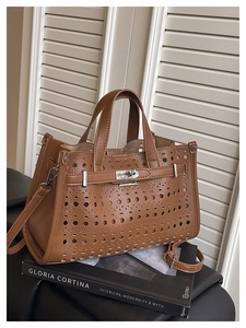 Detail of brown lychee leather handbag featuring laser-cut hollow pattern and silver twist lock