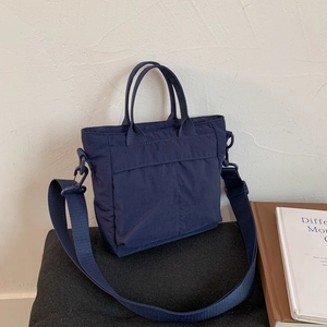 Detail of navy blue nylon tote bag with double handles and detachable wide shoulder strap