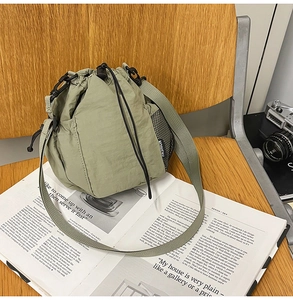 Detail of light green nylon bucket bag with drawstring closure and fashion label