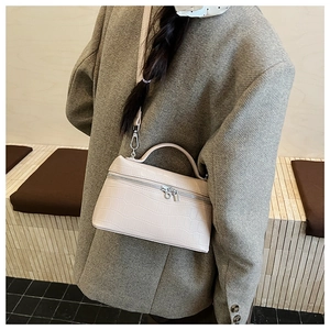 Detail of elegant beige crocodile-patterned handbag with silver dual zipper and top handle