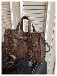 Detail of dark brown leather tote featuring circular cutouts and luxury metal buckle