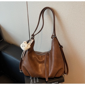 Detail of vintage brown hobo bag with pleated texture and plush bear charm