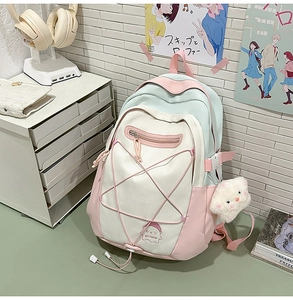 Macro detail of multi-color pastel nylon backpack with ghost embroidery and plush cat charm