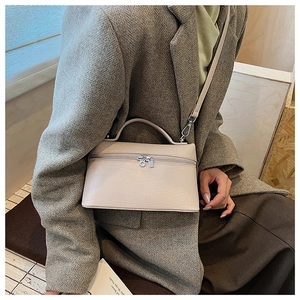 Detail of a beige crocodile pattern leather handbag styled with a grey wool blazer