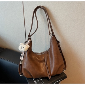 Close-up of brown vintage hobo bag with teddy charm on a decorative book stack