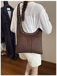 Sac à épaule en daim marron rétro avec rivets argentés porté par un mannequin