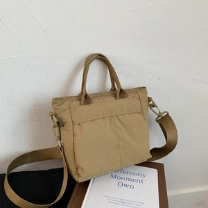 Detail of khaki nylon crossbody bag showing the fabric texture and durable webbing handles