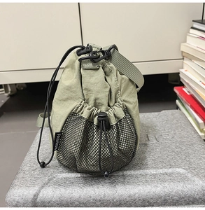 Detail view of light green nylon bucket bag with mesh side pocket and drawstring closure