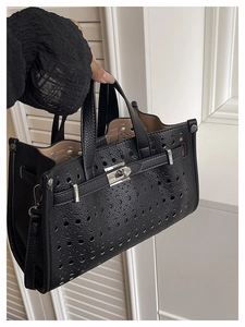 Detailed macro view of laser-cut hollow pattern on black leather tote with twist lock