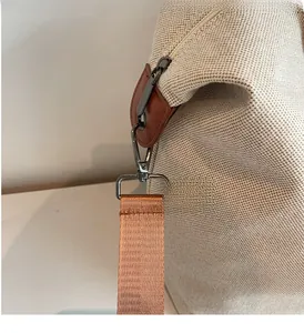 Detailed close-up of durable dark grey metal hook and nylon shoulder strap on canvas tote bag