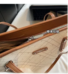 Dettaglio della cerniera in metallo argentato e logo sulla borsa tote color crema
