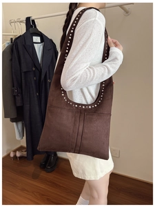 Détail du sac cabas en daim marron foncé avec rivets et deux poches frontales