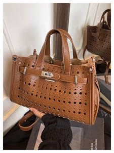 Close-up of brown leather tote bag with laser-cut hollow pattern and silver twist lock