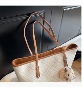Dettaglio della borsa tote beige a quadretti con manici in pelle e charm a coniglio
