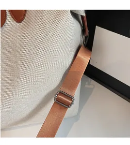 Detail of adjustable nylon shoulder strap and brown leather trim on canvas tote bag