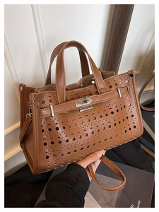 Close-up of brown hollow-out leather tote bag with silver turn-lock and fine stitching