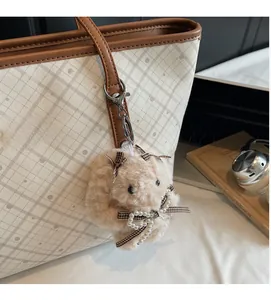 Dettaglio del ciondolo a forma di coniglio in peluche con perle su borsa beige