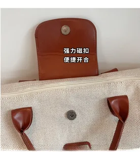 Detail of the magnetic buckle and metal zipper on this canvas tote travel bag
