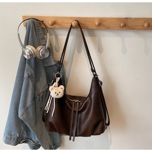 Detail of dark brown tote bag featuring silver zipper with long leather tassels