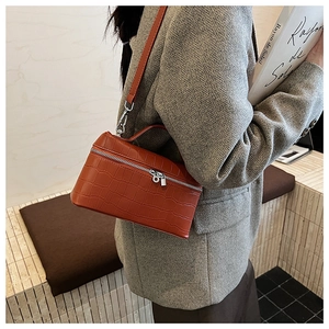 Detail of burnt orange crocodile pattern leather handbag with silver hardware and shoulder strap