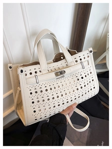 Detail of cream leather tote bag featuring geometric laser-cut patterns and metal lock