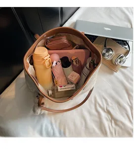 Vista dall'alto dello spazioso interno della borsa tote chiara con diversi oggetti quotidiani