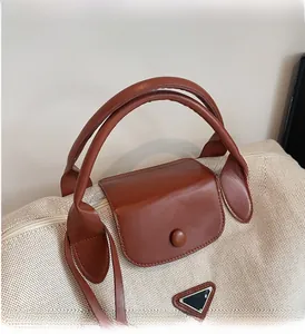 Detailed shot of canvas travel tote featuring leather handles and triangular metal logo