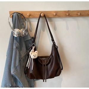 Detail of dark coffee vintage tote with double zippers and plush bear charm decoration