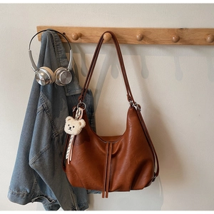 Detail of caramel brown vintage tote bag with plush bear charm and long tassel zipper