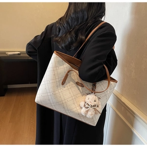 Dettaglio della borsa tote a scacchi bianca con manici in pelle marrone e charm a coniglio