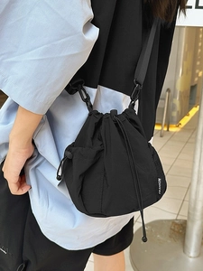 Black nylon drawstring bucket crossbody bag with side mesh pocket and fashion label