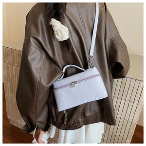 Detail of light purple crocodile texture small crossbody bag with top handle and strap