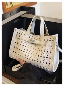 Detail of white hollowed leather handbag with silver lock shown in a premium gift set