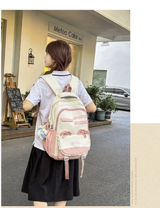Pink and beige school backpack featuring lace trim and ribbon bow on model