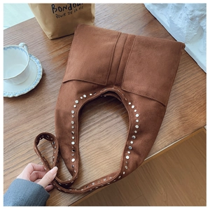 Gros plan du sac à bandoulière en daim marron avec rivets argentés sur bois