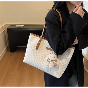Dettaglio della borsa tote a scacchi con finiture in pelle marrone e charm coniglio