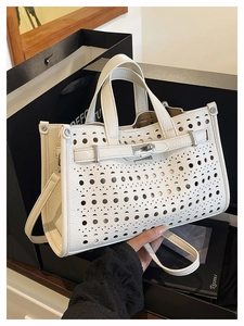 Detail of white laser-cut leather handbag with silver clasp and lychee grain texture