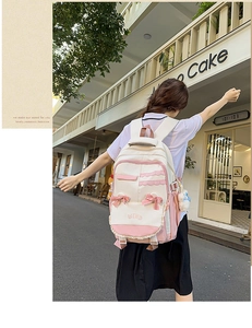 Detail of pink and white school backpack with silk bow, lace trim and plush pendant