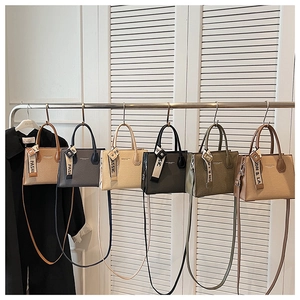 Six sacs à main colorés en cuir PU texturé suspendus sur un portant dans une pièce claire