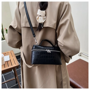 Fashionable black crocodile pattern box bag styled on a beige trench coat