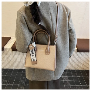 Détail du petit sac carré texturé avec finitions en cuir et sangle décorative tissée