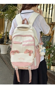 Detail of preppy backpack with lace edges, pink bow, and plush bear pendant detail