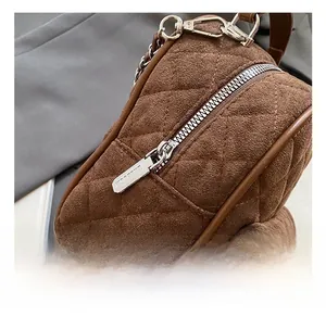 Detailed close-up of premium silver hardware and zipper on brown quilted suede backpack