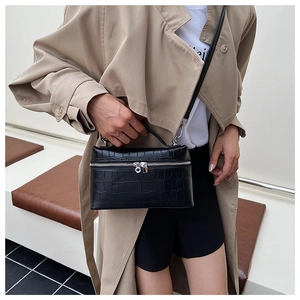 Detail of black crocodile texture box bag with silver zippers and adjustable strap
