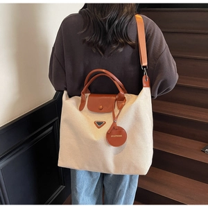 Canvas tote bag detail showing dual handles and adjustable shoulder strap on model back