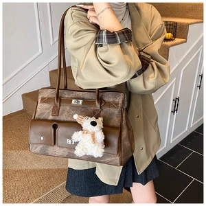 Detailed macro of vintage brown tote bag with metal buckles and a cute teddy bear charm