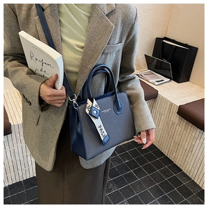 Vue détaillée d'un sac à main en cuir bleu marine avec un foulard en soie décoratif