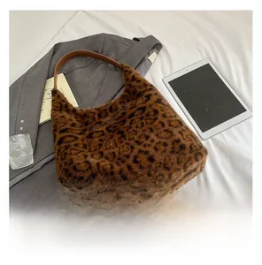 Flat lay of leopard print faux fur tote bag with brown leather handles and city life items